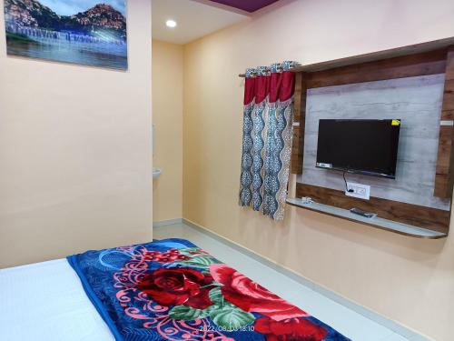 een slaapkamer met een flatscreen-tv aan de muur bij Abhi Homestay Hampi in Hampi