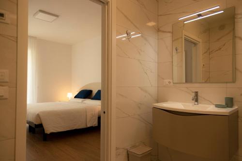 a bathroom with a sink and a bed and a mirror at HOLIDAY APARTMENTS GIULIA - Blue in Pietramurata