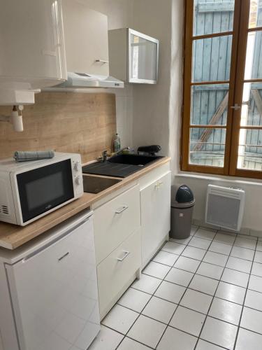 - une cuisine blanche avec un four micro-ondes et un évier dans l'établissement Carcassonne situé plein centre, à Carcassonne