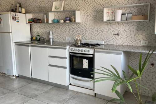 a white kitchen with a stove and a refrigerator at Departamento en San Nicolás de los Arroyos in San Nicolás de los Arroyos