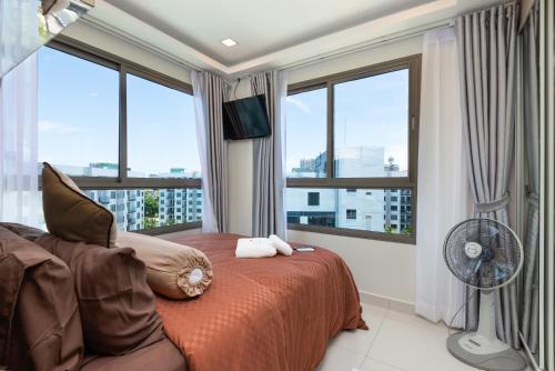 a bedroom with a bed with a fan and windows at Rare XXXL Swimming Pools Resort - Free Fast WIFI - Top Floor Pool View Balcony in Pattaya South