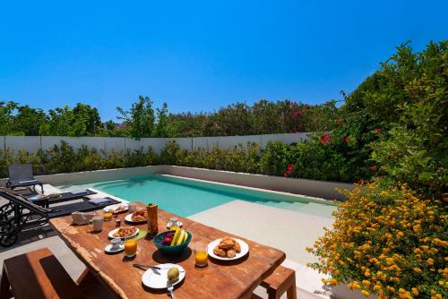 a table with food on it next to a swimming pool at Thalassa Luxury Villa in Ialyssos