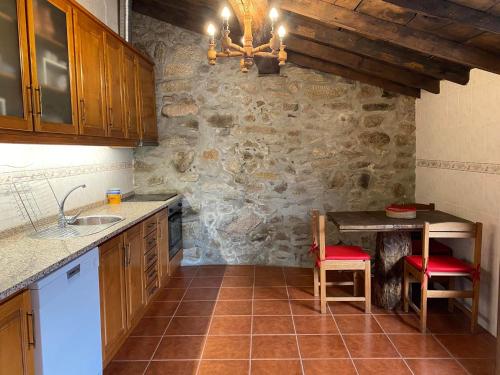 a kitchen with a table and a stone wall at Casa da Pipela 