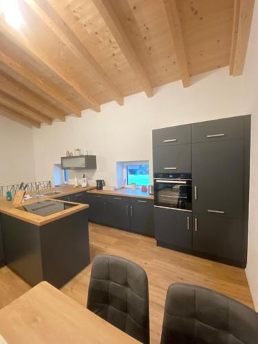 a kitchen with black cabinets and a wooden floor at Apartment in der Au in Langkampfen