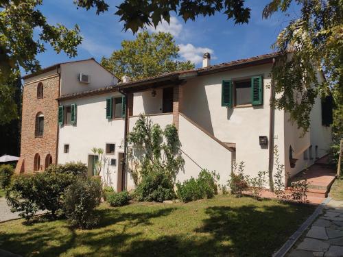 Casa blanca con persianas verdes y patio en Podere Borgaruccio, en Peccioli