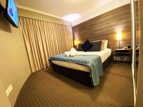een hotelkamer met een bed en een televisie bij 2 Bed 2 Bath Apartment in Braddon, Canberra - Pool, Gym and Free Parking in Canberra