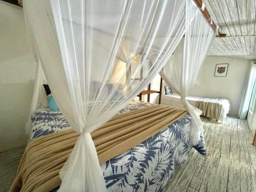 a bedroom with a canopy bed with white curtains at VILA TRANCOSEAR in Trancoso