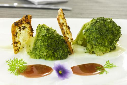 a plate of food with broccoli and a purple flower at RuralSuite Hotel Apartamentos in Cascante