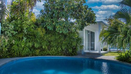 a swimming pool in front of a house with trees at Contemporary Private Studio with Pool and Kitchen in Beira
