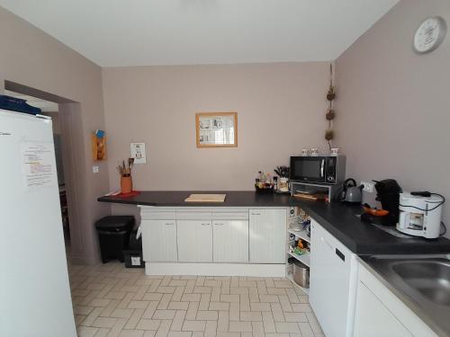 uma cozinha com armários brancos e um balcão preto em Au doux refuge em Saint-Exupéry-les-Roches