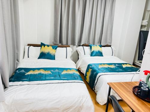 a bedroom with two beds with blue and yellow pillows at 福宿 Fukuinn 301号室 in Takamatsu