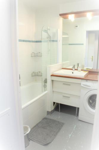 La salle de bains blanche est pourvue d'un lavabo et d'un lave-linge. dans l'établissement Logement familial tout équipé (1 station de Paris), à Saint-Denis