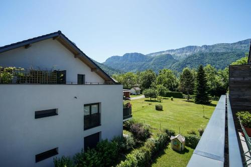 a white building with a yard and mountains in the background at The Azalea beautiful quiet apartment for 4 people! in Doussard