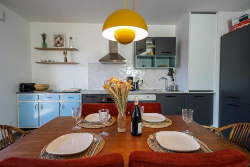 a kitchen with a wooden table with plates and wine glasses at The Azalea beautiful quiet apartment for 4 people! in Doussard