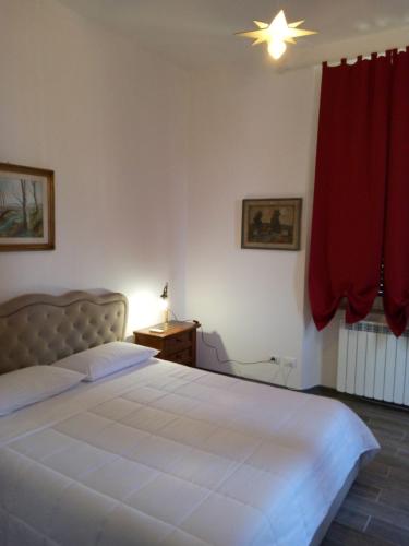 a bedroom with a white bed and a red curtain at Notte Rosa Suites & Relax in Fornovo di Taro