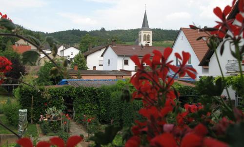 a village with a church in the background with red flowers at Zur Rotenfelsstube in Traisen