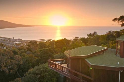a house with the sun setting over the water at Kinoie Mornington - OCEANVIEW in Mount Martha