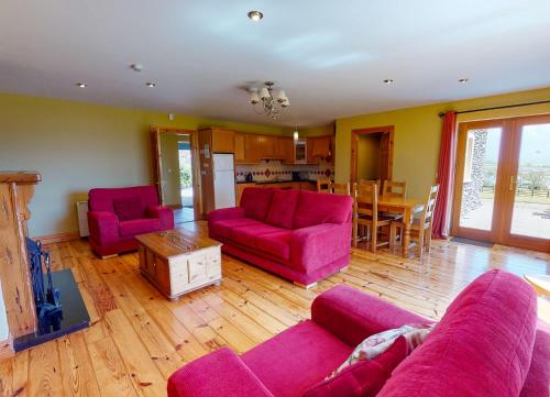 a living room with pink furniture and a kitchen at Dingle Courtyard Cottages 4 Bed Sleeps 8 in Dingle