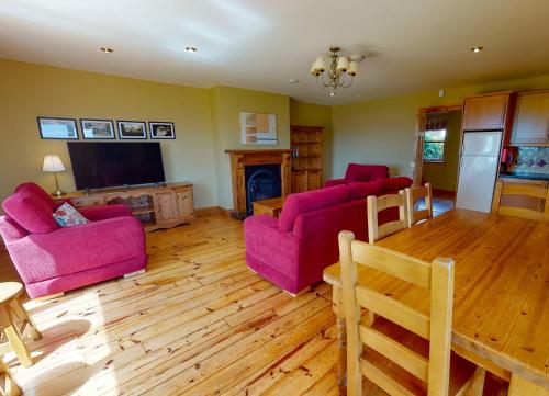 a living room with pink furniture and a tv at Dingle Courtyard Cottages 4 Bed Sleeps 8 in Dingle