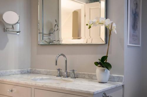 La salle de bains est pourvue d'un lavabo et d'un vase avec une fleur. dans l'établissement The Lodge, à New Milton
