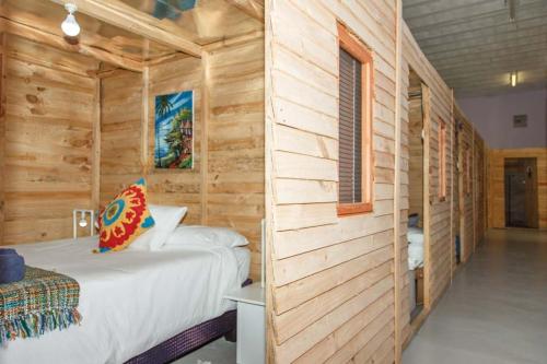 a bedroom with a bed in a wooden wall at Bokkomblommetjie in Lambertʼs Bay