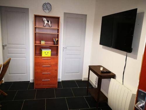 a room with a tv and a dresser with a clock at L'écurie in Chanceaux-sur-Choisille