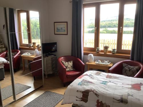 a bedroom with a bed and chairs and windows at Doura Lodge in Inverness