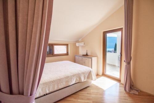 sypialnia z łóżkiem i dużym oknem w obiekcie Boka Apartment w mieście Baošići
