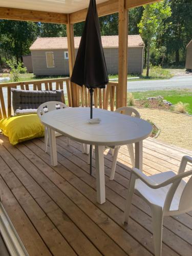 una mesa blanca y sillas en una terraza con sombrilla en Chalet, en Labouheyre