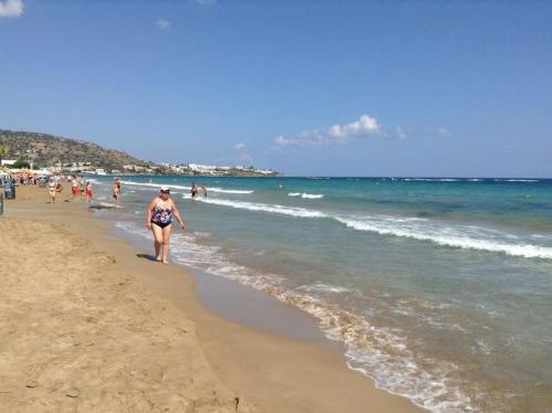 a woman walking on a beach near the ocean at Creta Solaris Holiday Apartments in Stalís