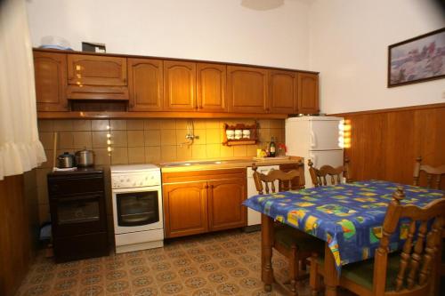 a kitchen with wooden cabinets and a table with a blue table cloth at Apartments and rooms by the sea Sumpetar, Omis - 2099 in Jesenice