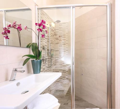 a bathroom with a sink and a shower with pink flowers at Alma di Alghero Hotel in Alghero