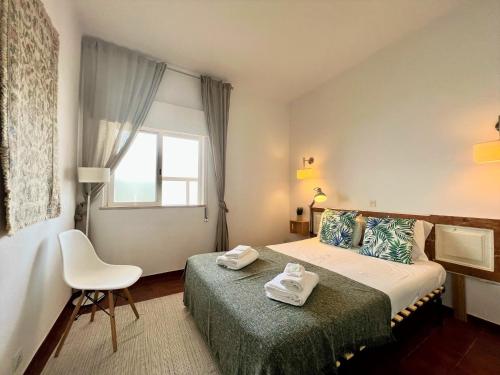 a bedroom with a bed and a chair and a window at Armação de Pêra Twins 2 With Pool by Homing in Armação de Pêra