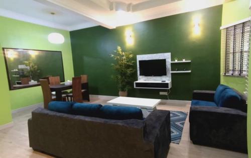 een woonkamer met groene muren en een bank en een tv bij HOMESTAY DR. Z (MUSLIM HOMESTAY) in Klang
