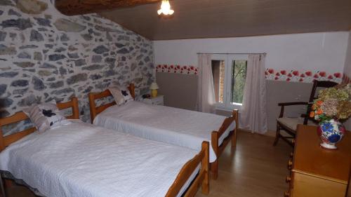 1 dormitorio con 2 camas y pared de piedra en Gîte Les Mimosas en Prugnanes