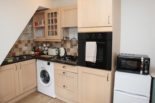 une cuisine équipée d'une cuisinière et d'un lave-linge et sèche-linge dans l'établissement Millgate Cottage in the heart of Richmond, à Richmond