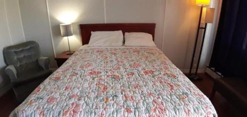 a bedroom with a bed with a floral bedspread at Regal Motel in Timmins