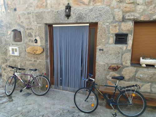 El Bosque de los Romanos في Puerto de Béjar: اثنين من الدراجات متوقفة أمام مبنى حجري