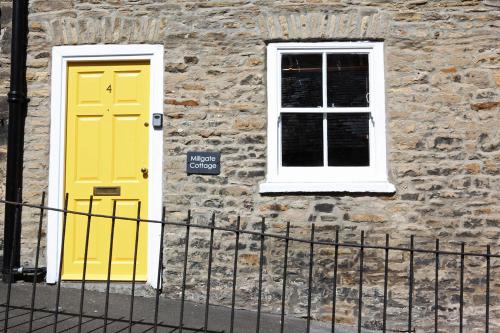 dos puertas amarillas en un edificio de piedra con una valla en Millgate Cottage in the heart of Richmond en Richmond