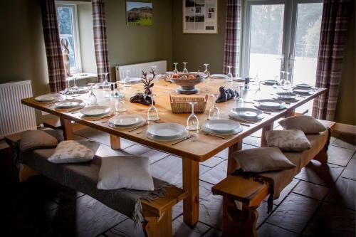 a long wooden table with chairs and plates on it at The Ynys Lodge in Pwllheli