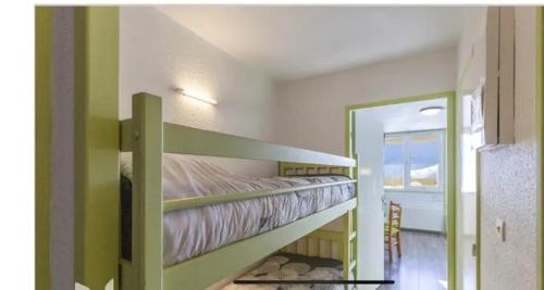 Ce lit superposé vert se trouve dans un dortoir doté d'une porte. dans l'établissement Le perchoir de Juliette, à La Mongie