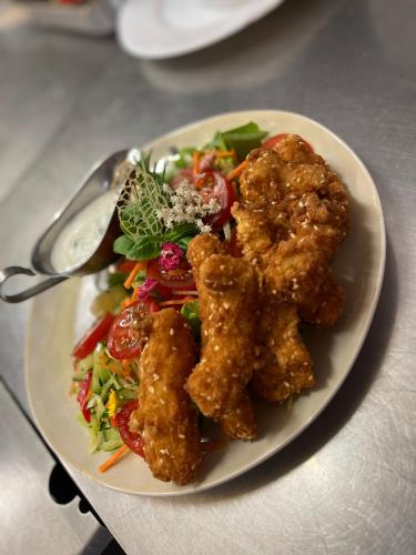a plate of food with chicken tenders and a salad at Malom Club Panzió in Baja