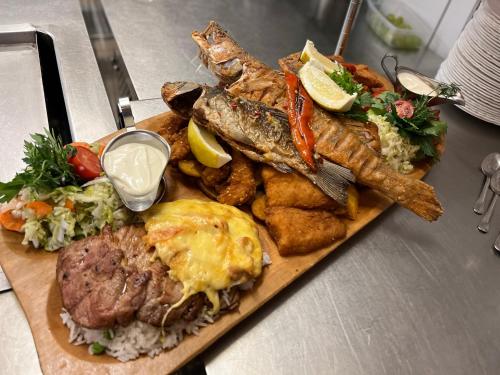 a plate of food with fish rice and other foods at Malom Club Panzió in Baja