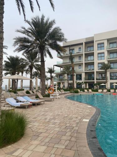 a resort with a swimming pool and palm trees at Two Bedroom Apartment Address Residence - Fujairah in Fujairah