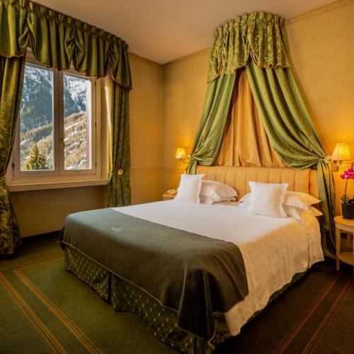 a bedroom with a large bed with green curtains at Grand Hotel Royal E Golf in Courmayeur