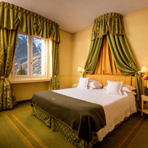 a bedroom with a large bed and a window at Grand Hotel Royal E Golf in Courmayeur