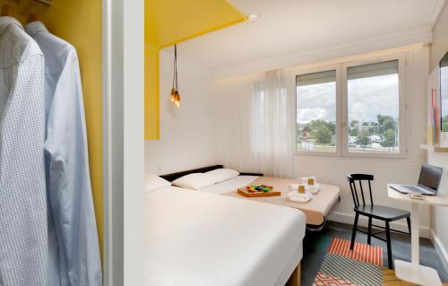 a room with two beds and a table and a window at Hôtel ibis Styles Auxerre Nord in Auxerre