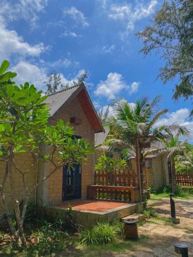 a house with a fence and a palm tree at Long Hải Channel Beach Resort in Long Hai