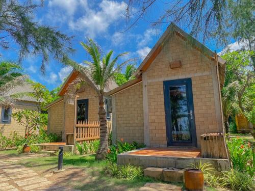 a house with a palm tree in front of it at Long Hải Channel Beach Resort in Long Hai