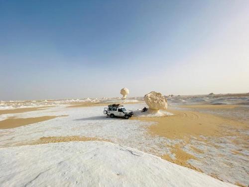 a jeep parked on a sandy beach in the ocean at Rahala Safari Hotel in Qasr Al Farafirah